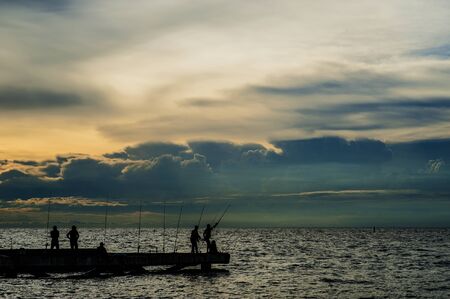 Fisherman local silhouette on thai sea with clouds orange skyの写真素材