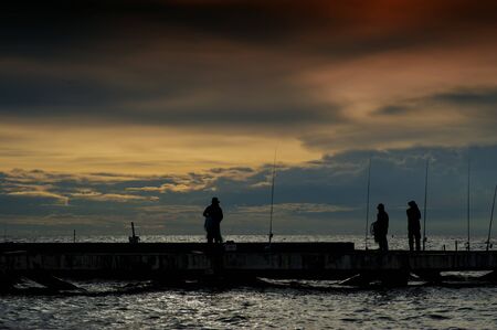 Fisherman local silhouette on thai sea with clouds orange skyの写真素材
