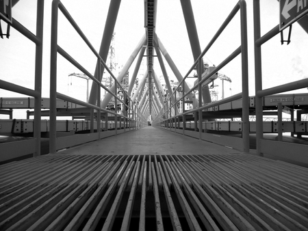 Bridge platform connected between wellhead platform and central processing platform that is route of support of oil and gas piping from remote to central processing platform underneath bridgeのeditorial素材