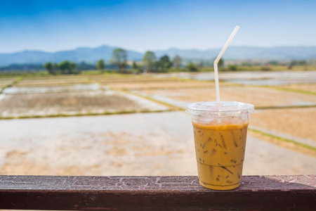 ice coffee, a cup of ice coffee in wood with field, rice, farm and blue sky.の写真素材