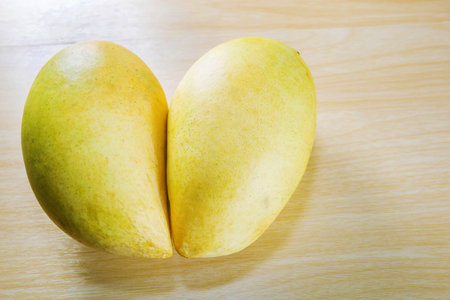 two yellow mangoes in heart shape on tableの写真素材