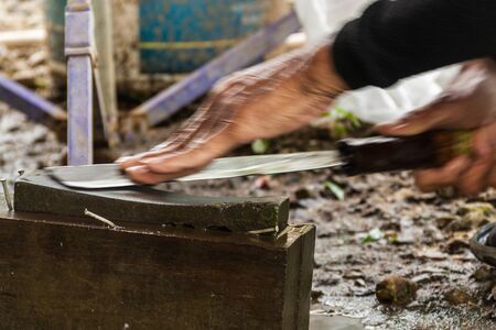 Knife whetting, Thai villager is whetting the knife before cooking the meal.