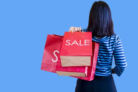 Shopping sale woman showing shopping bag with sale written.  showing red shopping bags.  in colorful blue  background,  sale conceptの写真素材