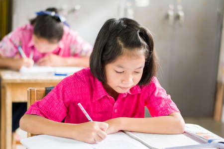 Female Asian students. The pink uniform female student to sit exams in the classroom in the classroom of rural schools in Thailand.の写真素材