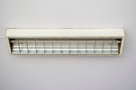 Old and rusty Square box neon lamp. and fluorescent tube hanged on a concrete grungy ceiling. End-of-Life Devices Waiting for a new replacement. Change to a new generation of modern equipment.の写真素材