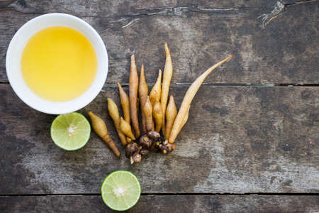 Kaempferia, honey, and lemon are placed on wooden table with old textures with copy space. medicinal for Thai food, anti-Covid-19 extract. Take photo on top view. natural medicinal plant concept.の写真素材