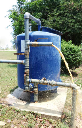 Purification filter equipment water supply system from groundwater,  Large metal tanks for filtering, potable water treatment from well-Drinking water factory. with Muddy flows from a metal pipe.の写真素材