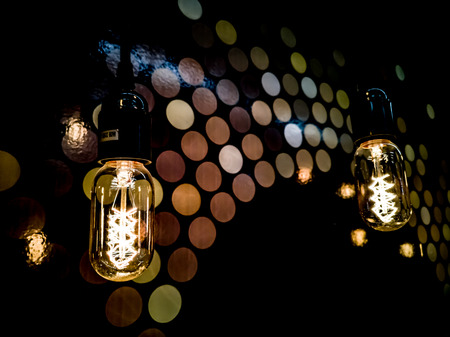Tungsten orange light bulb hanging on the inside of the building with a black iron fence around,Lighting in buildings with multi-colored electric lamps,soft focus.high contrast format.の写真素材