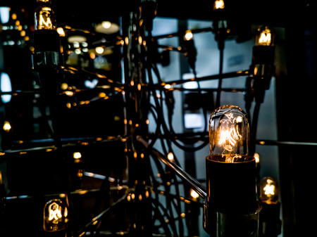 Tungsten orange light bulb hanging on the inside of the building with a black iron fence around,Lighting in buildings with multi-colored electric lamps,soft focus.high contrast format.の写真素材