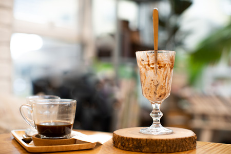 Clear glass with the remains of ice cream and brown wooden spoons. The coffee is eaten. On the table...