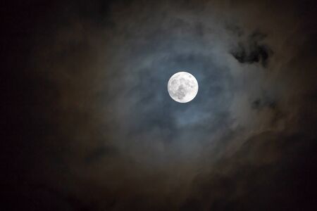 Full moon on the dark night shining on the sky in cloudy day.の写真素材