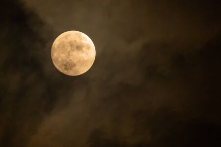 Full moon on the dark night shining on the sky in cloudy day.
