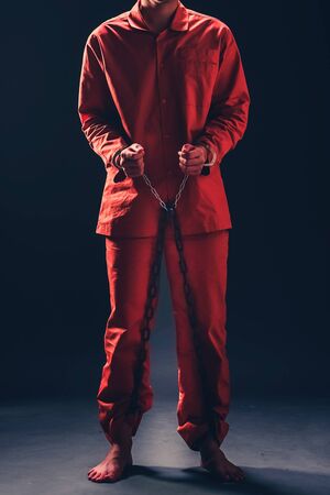 Prisoners in orange robes  Chained and handcuffed on a gray background.soft focus.の写真素材