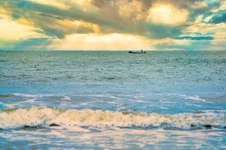 Shallow depth of field shot of Sea water Blurred white wave bubble images and Golden evening sky.at Chanthaburi Coast, Thailand.soft focus.の写真素材