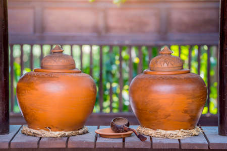 Shallow depth of field shot of Garlic Bread In a red enamel container, on a Thai wooden tableの写真素材