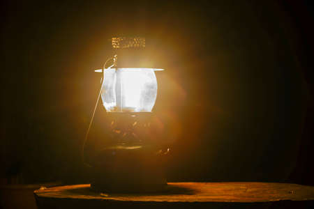 Lantern on a wooden table in a dark room. Vintage lamp on a dark background.