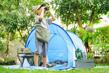 happy boy in camping tent.boy holding binoculars in adventure time.soft focus.の写真素材