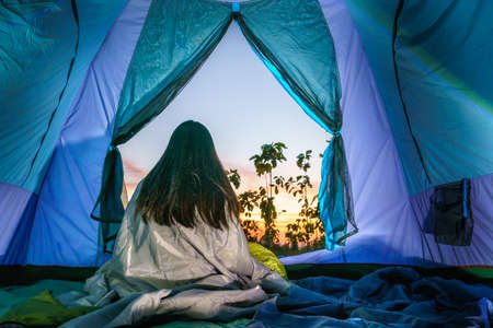 young girl relax inside the tent in the morning at sunrise in the forest. soft focus.の写真素材