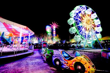 Amusement park at night with big wheel and ferris wheelの写真素材