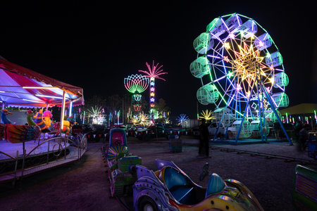 Amusement park at night with a ferris wheel and peopleの写真素材