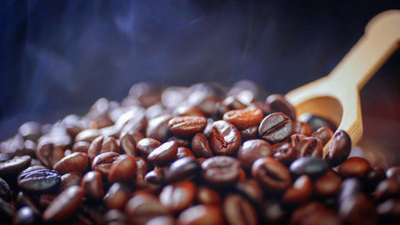 Coffee beans and wooden spoon on a dark background with smokeの写真素材