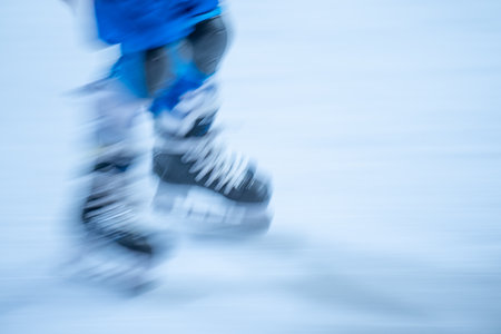 Blurred movement of skates on an outdoor ice rink. Young girl skating thinking on the open rinkの写真素材