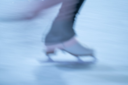 Blurred movement of skates on an outdoor ice rink. Young girl skating thinking on the open rinkの写真素材