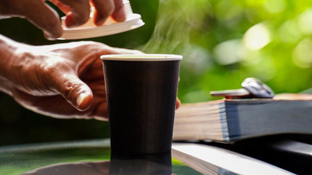 coffee takeaway in a paper cup on top of the car roof green tree background at sunrise in the morning,  selective focus, soft focus.の写真素材