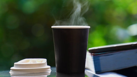 coffee takeaway in a paper cup on top of the car roof green tree background at sunrise in the morning,  selective focus, soft focus.の写真素材
