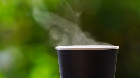 coffee takeaway in a paper cup on top of the car roof green tree background at sunrise in the morning,  selective focus, soft focus.の写真素材