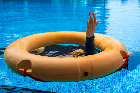 Top view of lifebuoy floating in blue swimming pool, soft focus.