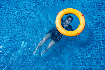 Top view of lifebuoy floating in blue swimming pool, soft focus.の写真素材