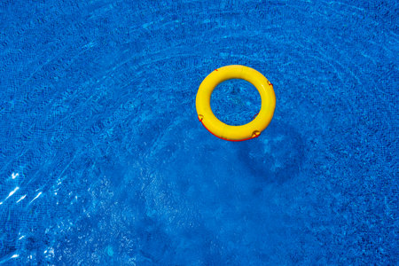 Top view of lifebuoy floating in blue swimming pool, soft focus.の写真素材