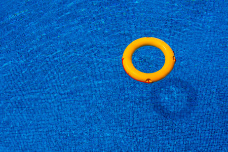 Top view of lifebuoy floating in blue swimming pool, soft focus.の写真素材