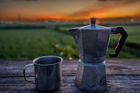 Hot coffee and Moka pot with the sunrise background.coffee cup on the wooden table with the sunrise background.soft focus.の写真素材