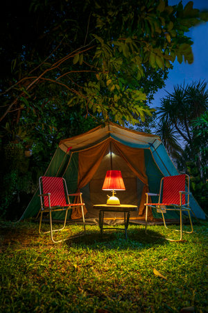 vintage cabin tent,  Antique oil lamp on a wooden table with retro chairs. at night in the  forestの写真素材