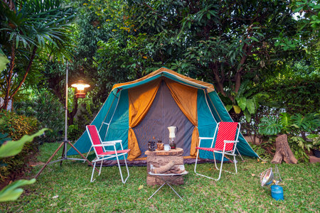 vintage cabin tent,  Antique oil lamp, retro chairs, Group of camping tents with outdoor coffee-making facilities on wooden tables in a forest camping area in the forest.の写真素材