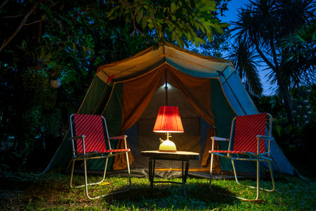 vintage cabin tent,  Antique oil lamp on a wooden table with retro chairs. at night in the  forestの写真素材