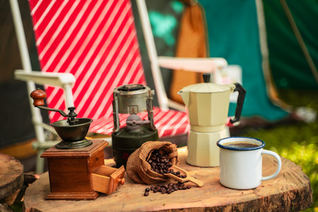 selective focus of vintage coffee set on the old wooden table In front of the retro cabin tent, Antique oil lamp, retro chairs, Group of camping tents, and soft focus.の写真素材