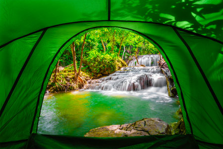 looking from inside the tent to view in the emerald blue water in Erawan National Park. Erawan Waterfall is a beautiful natural rock waterfall in Kanchanaburi, Thailand.の写真素材