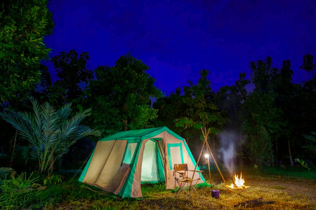Camping tents at night, vintage cabin tents, antique oil lamps, retro chairs, and a group of camping tents with outdoor  facilitiesの写真素材