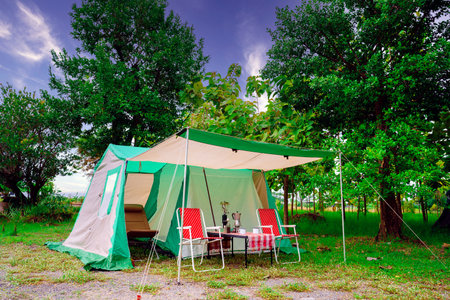 Camping tents, vintage cabin tents,  Antique lanterns, retro chairs, and outdoor coffee-making facilities on wooden tables in a forestの写真素材