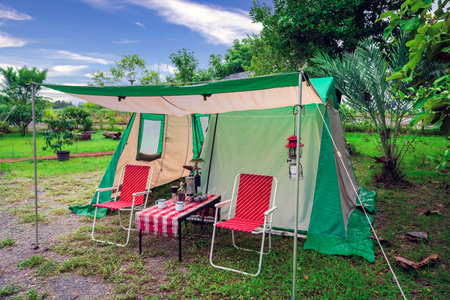 Camping tents, vintage cabin tents,  Antique lanterns, retro chairs, and outdoor coffee-making facilities on wooden tables in a forestの写真素材
