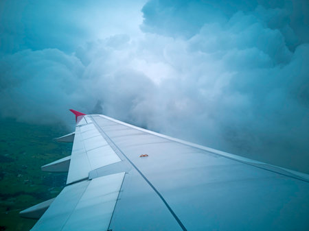 wings of airplane during the flight look from the passenger window. There are white clouds in the blue sky.の写真素材