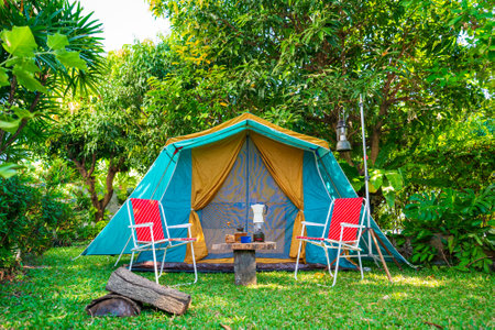 Camping tents, vintage cabin tents,  Antique lanterns, retro chairs, and outdoor coffee-making facilities on wooden tables in a forestの写真素材