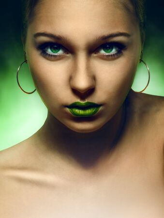 portrait of girl with green eyes and lips on green backgroundの写真素材