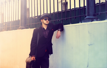Elegant man in a hat standing near the wall の写真素材