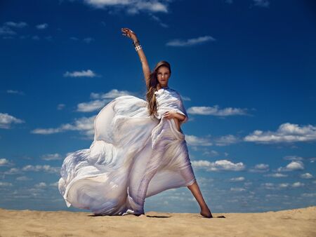 elegance woman in long white dress in desertの写真素材