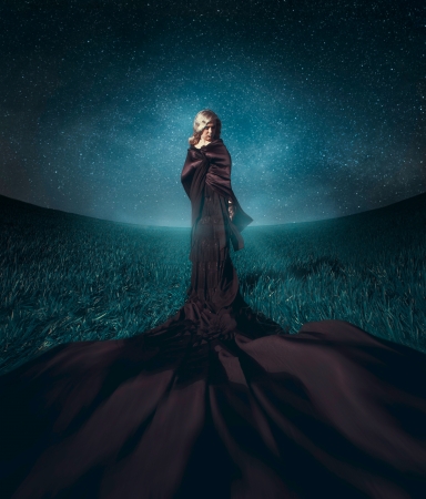 charming blonde stand in the fielnd against the background the starry skyの写真素材