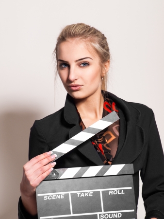 portrait of pretty girl with film slate in studio on gray backgroundの写真素材